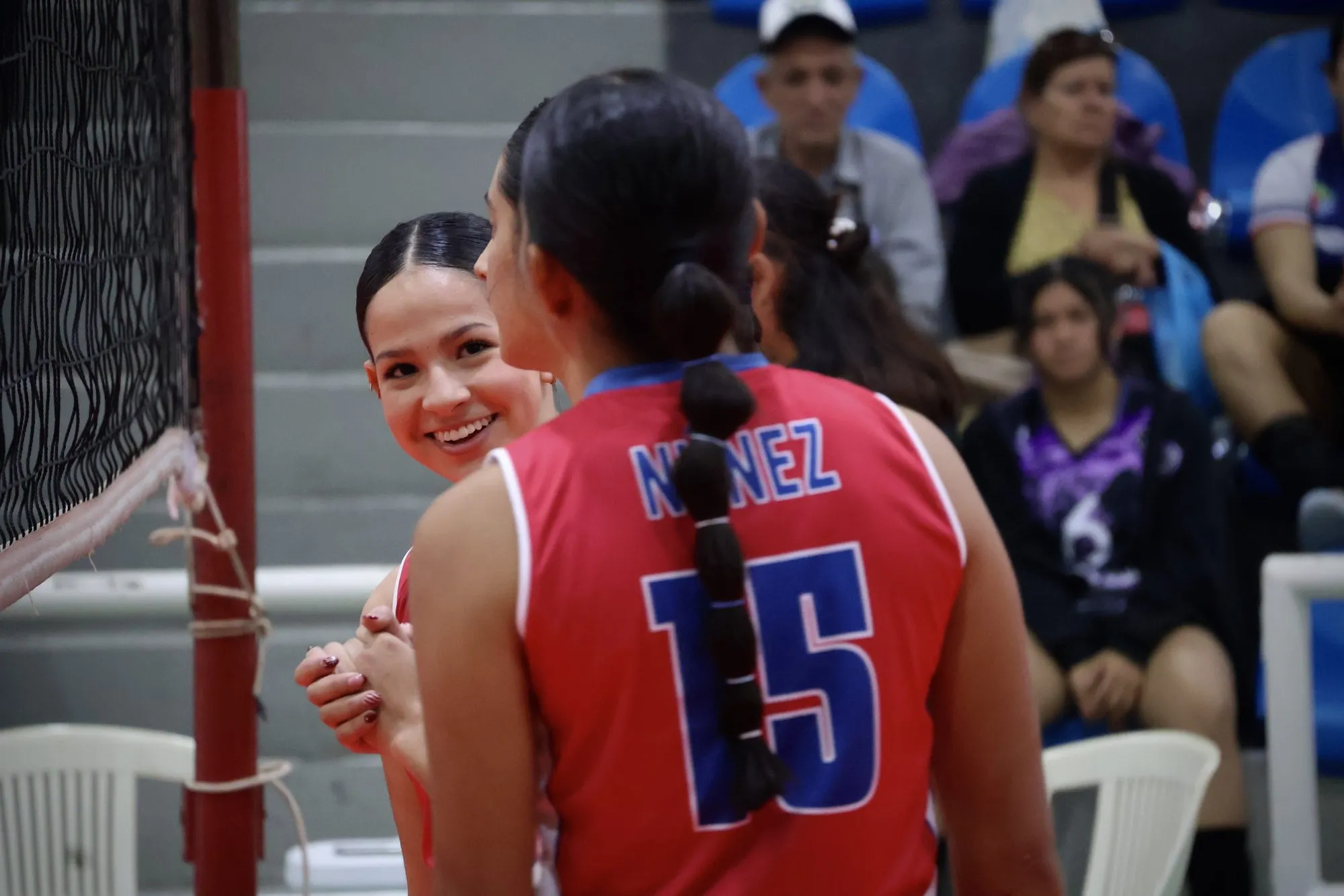 Dos compañeras se saludan sonriendo antes de entrar a la cancha.