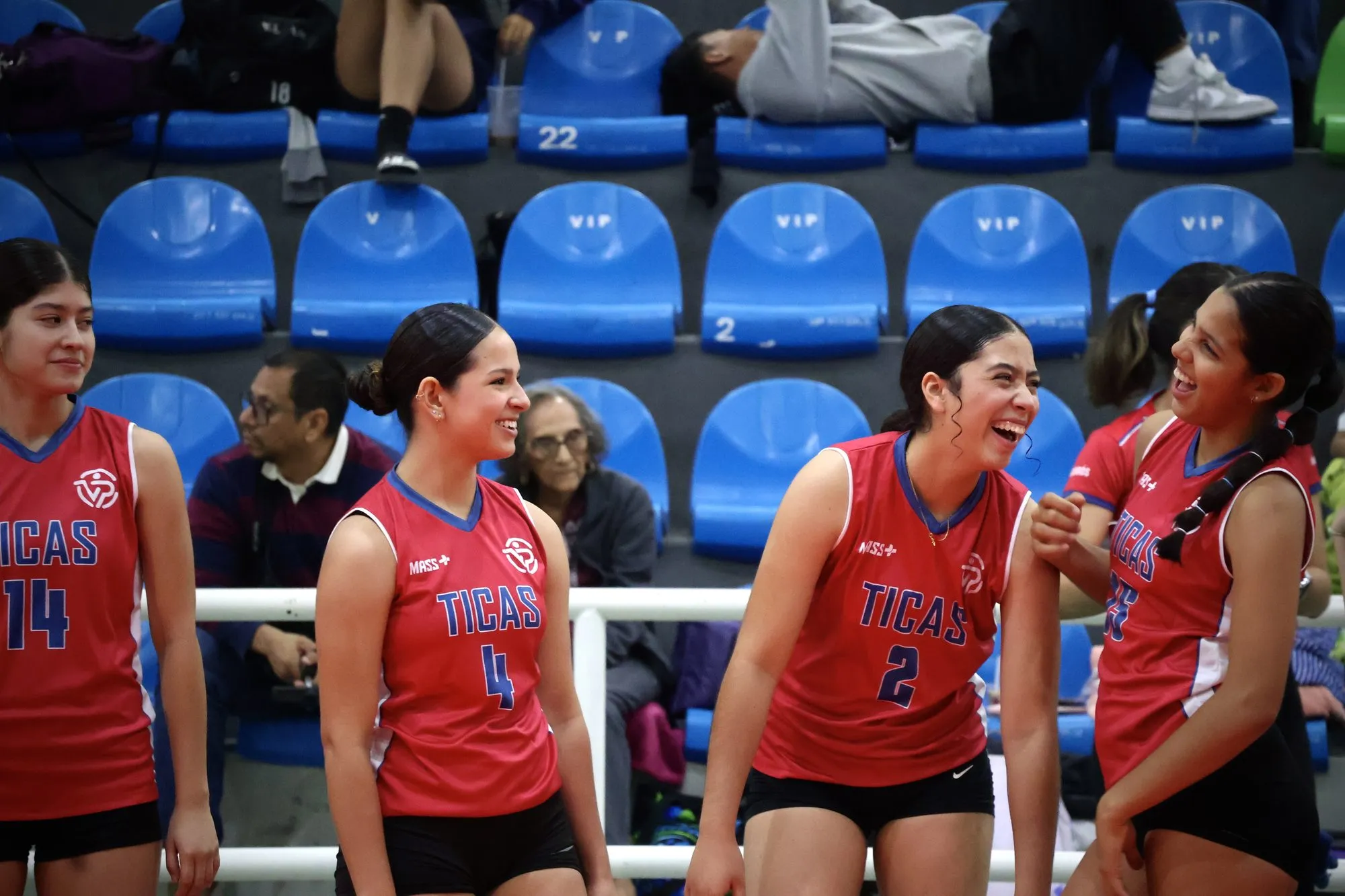 Cuatro compañeras del equipo costarricense conversan y ríen al borde de la cancha.