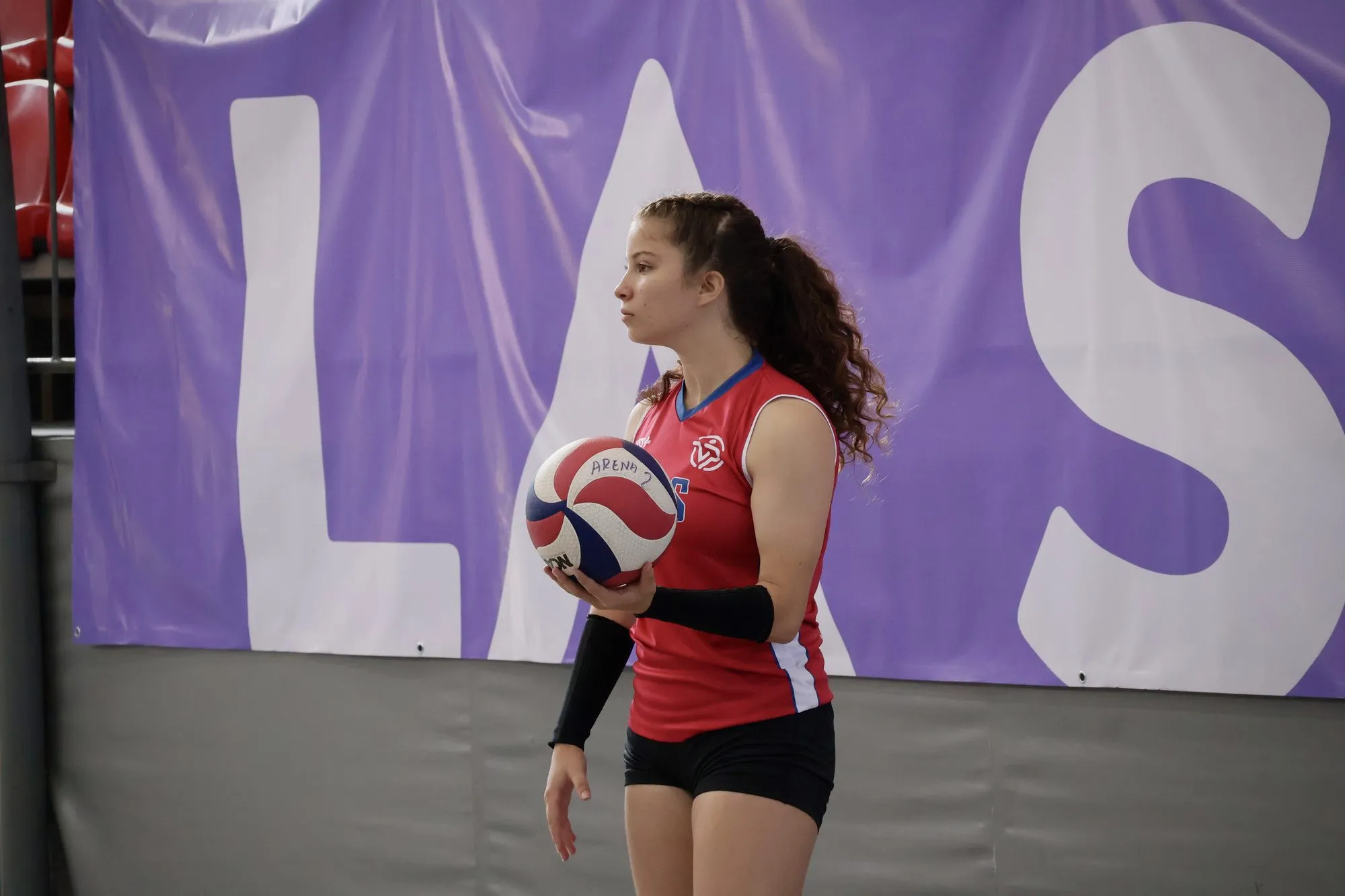 Una jugadora espera con el balón en las manos delante del telón del torneo.