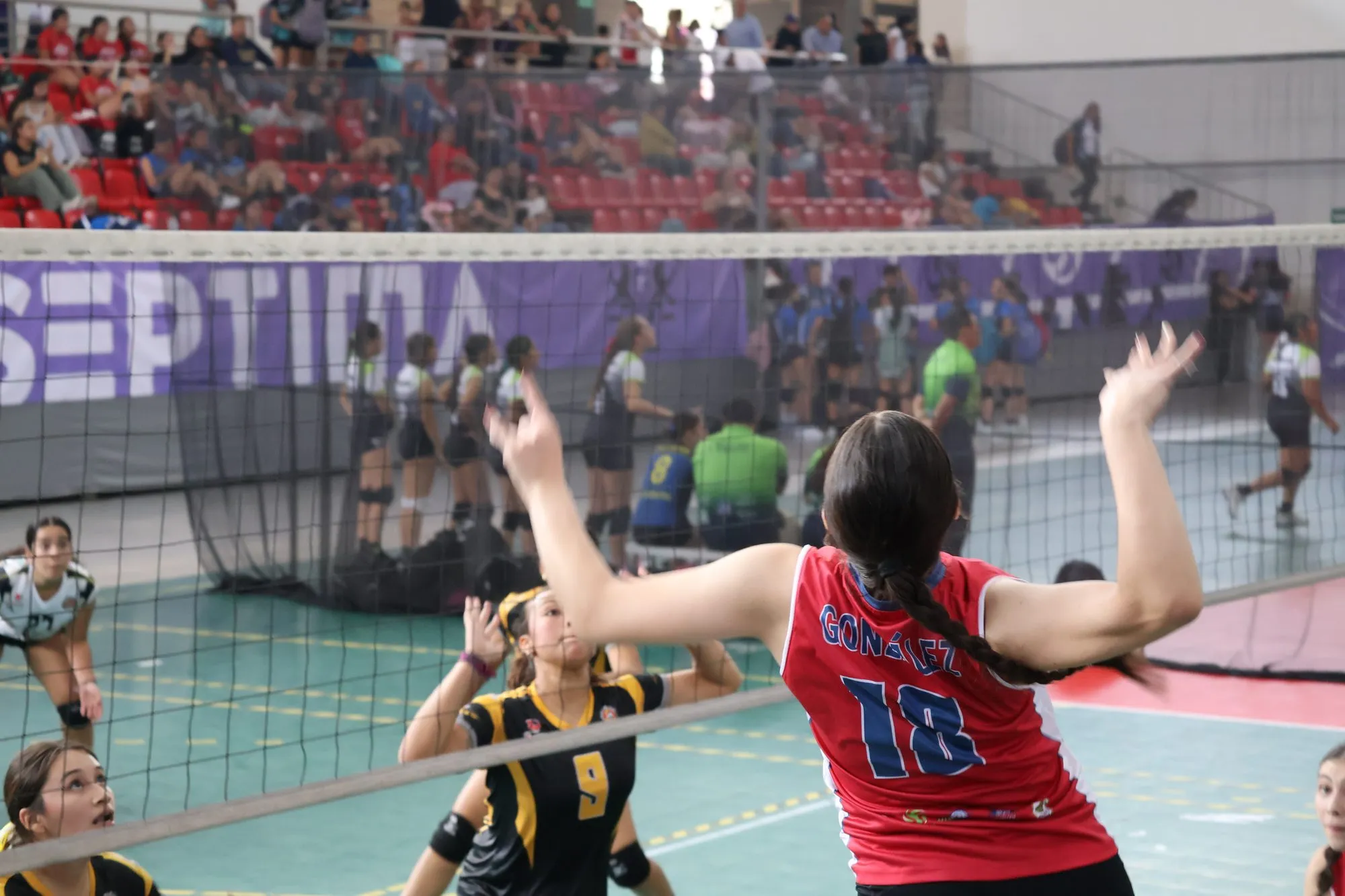 Una jugadora levanta las manos en la red frente a una rival, con el balón cerca de la cinta.