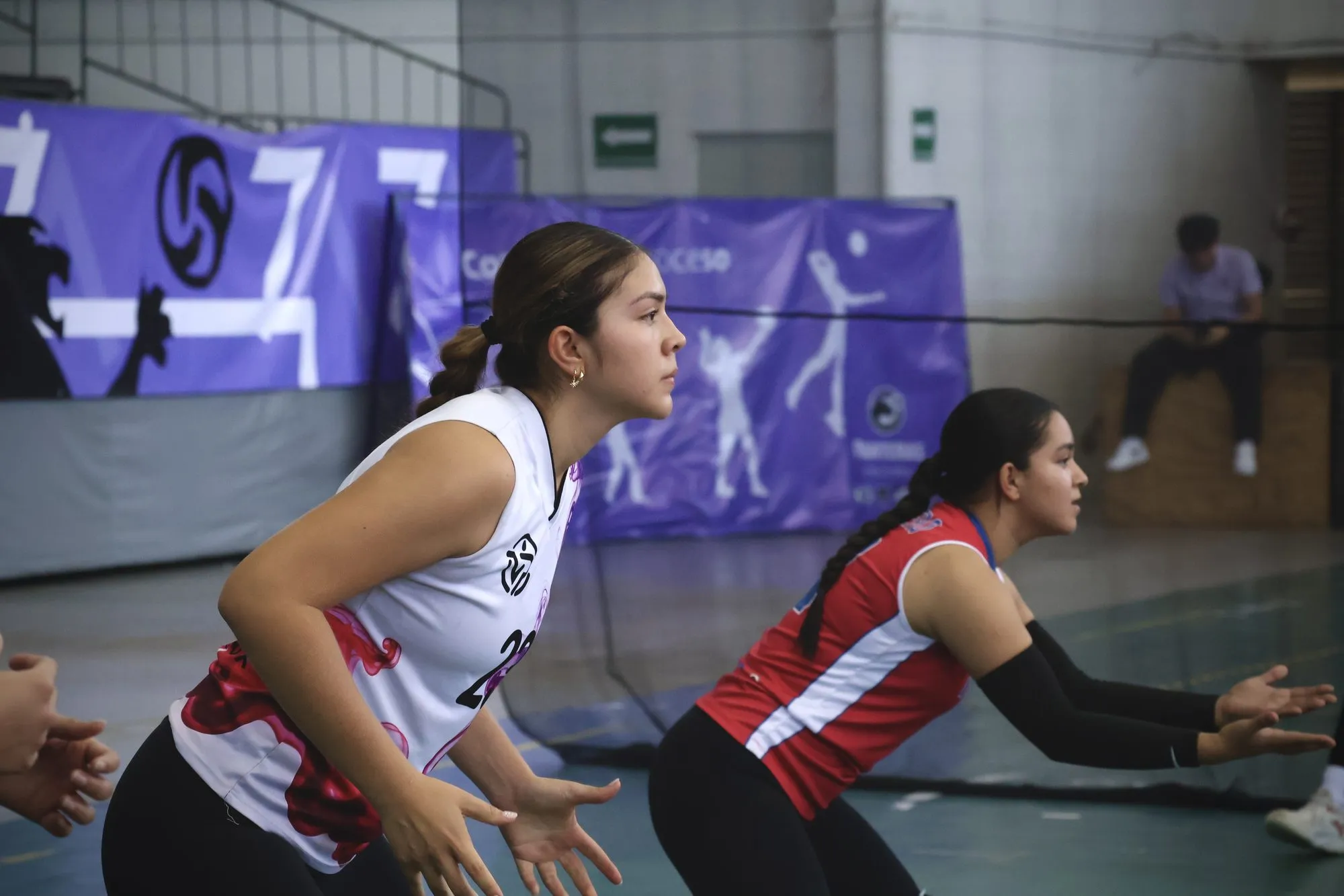 Dos jugadoras esperan agachadas el ataque rival, con los brazos listos para defender.