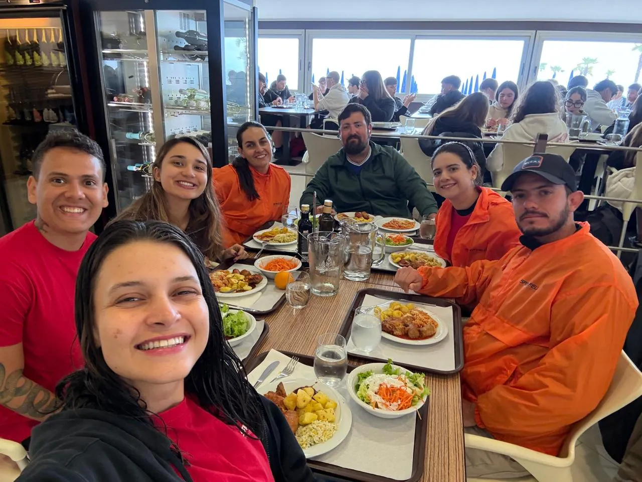 El grupo comparte el almuerzo en una mesa larga junto a la playa.