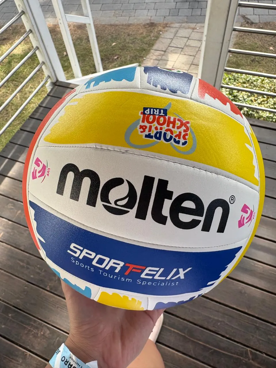 Balón oficial del encuentro sostenido en la mano, con el logo de Sport & School Trip.