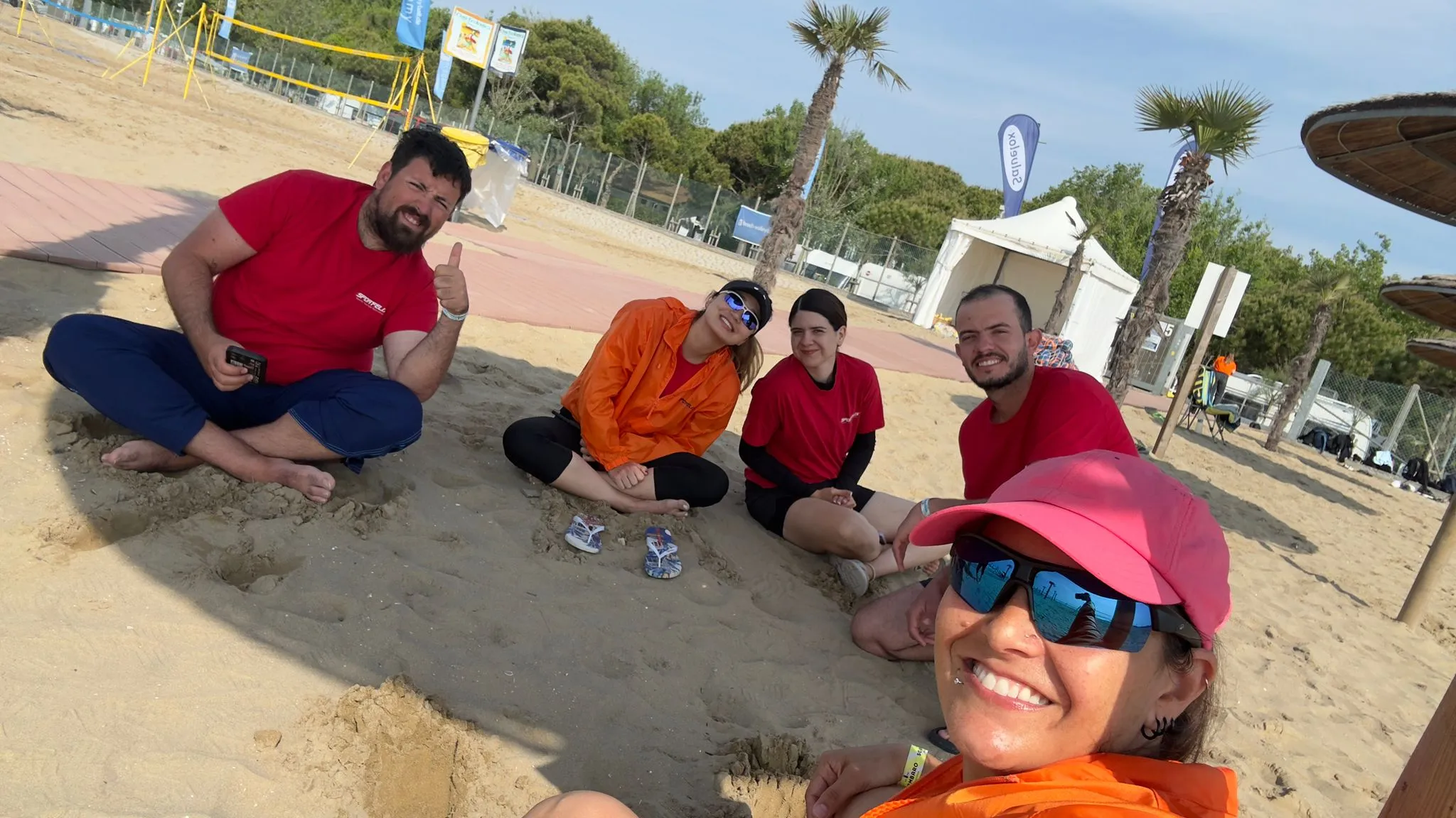 El grupo sentado en la arena entre sesiones de entrenamiento, en un día soleado.
